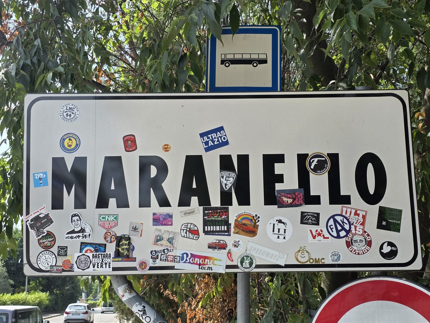 Mit Aufklebern geschmücktes Ortsschild von Maranello